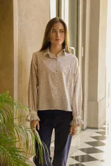 Camisa de algodón con estampado floral, cuello clásico, cierre frontal con botones, mangas largas con puños fruncidos y detalle de puntilla en puños y espalda.