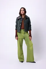 Campera corta de poliéster texturizado color verde oscuro, con cuello camisero, cierre frontal con botones a presión, bolsillos delanteros y forro interior. Incluye pins decorativos.