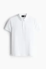 Remera polo blanca de manga corta en piqué liviano de mezcla de algodón con cuello y tapeta de botones. Corte ajustado que realza el contorno del cuerpo creando una silueta entallada. Confeccionada con tejido funcional COOLMAX®, una fibra exclusiva de poliéster de secado rápido que elimina la humedad y regula la temperatura corporal proporcionando un ajuste cómodo y suave.