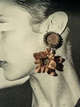 Aros colgantes con base circular con strass y dije de flor color cobre con strass en el centro.