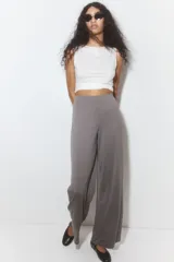 Pantalón gris de punto suave, tiro alto, corte amplio y cintura elástica.