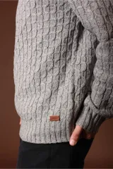 Sweater verde oliva de punto trenzado con cuello redondo y mangas largas.