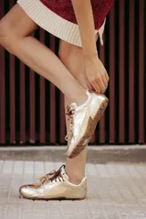 Zapatillas urbanas de cuero color tostado, con cordones verdes y suela de goma.