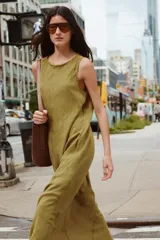 Vestido midi color ocre, de cuello redondo ajustable con cordones y sin mangas. Presenta bolsillos laterales ocultos en la costura y cierre trasero con botones.