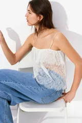 Top blanco de encaje con breteles finos y escote recto con volado festoneado.