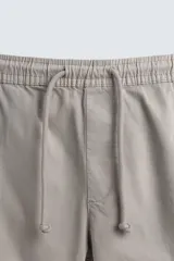 Pantalón cargo negro de corte slim fit, confeccionado en tejido de algodón con cintura elástica ajustable con cordón. Cuenta con bolsillos frontales, traseros y bolsillos tipo parche con solapa en los laterales.