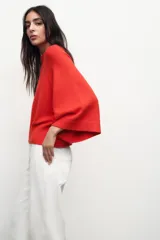 Sweater de punto color naranja con cuello redondo y mangas anchas hasta el codo.