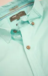 Camisa amarilla de algodón orgánico, manga larga con botones de madera, cuello italiano, calce regular, bolsillo de pecho con logo bordado.