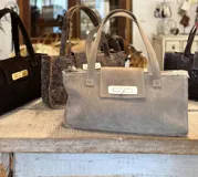 Bolso tote marrón con textura símil cocodrilo, cierre dorado y doble asa de mano.