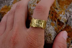 Anillo plateado con textura irregular y diseño rústico.