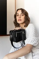 Bandolera rectangular de cuero color nude con doble compartimento con cierre de cremallera plateada y correa de cuero ajustable.