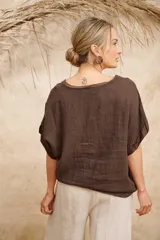 Blusa color crudo de lino con escote redondo y mangas cortas. Presenta apliques florales de razo y strass en el frente.