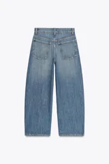 Pantalón de jean azul oscuro, tiro medio, corte amplio tipo baggy balloon con costuras torcidas y cinco bolsillos. Cierre frontal con cremallera y botón metálico.