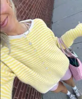 Buzo tejido a rayas horizontales rojas y blancas, con cuello tipo camisa y abotonadura frontal.