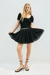 Blusa negra con escote cuadrado, mangas cortas abullonadas con elástico en hombros y puños, cintura fruncida y abertura con cordón para ajustar en el delantero.