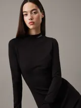 Vestido corto negro de punto milano con cuello perkins, mangas largas y corte ajustado. Logo de Calvin Klein bordado en el cuello.
