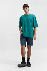 Remera verde esmeralda de manga corta con calce oversize, cuello redondo y estampado frontal con texto en azul.