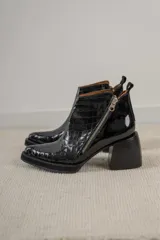 Botines negros de cuero con estampado de cocodrilo, cierre lateral con cremallera y tacón ancho.