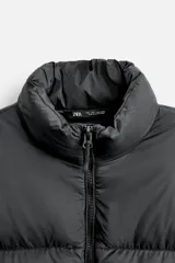 Campera puffer marrón con cuello alto, cierre frontal con cremallera, bolsillos laterales y puños elásticos.
