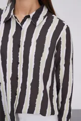 Camisa de manga larga con estampado a rayas verticales en tonos negro, blanco y verde claro.