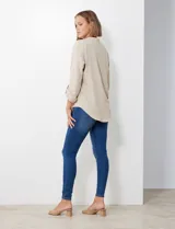 Blusa de gasa color beige, con cuello a la base y escote en V. Manga larga con presilla y botón para ajustar el largo.