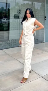 Camisa sin mangas color off-white, con cuello camisero, cierre frontal de botones y dos bolsillos de parche en el pecho.