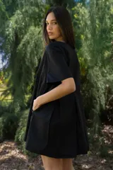 Vestido corto de algodón a cuadros color crema, verde y borgoña, con cuello redondo y mangas cortas. Presenta tablas en la parte delantera y trasera.