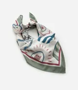 Pañuelo de satén con estampado tropical que incluye palmeras, casas, olas y otros íconos que recuerdan a las brasilidades. Presenta un borde verde y detalles en rojo, azul y rosa.