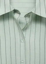 Camisa celeste a rayas verticales, de corte cropped, manga larga con puños abotonados, cuello camisero y cierre frontal con botones.