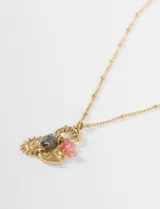 Collar de cadena plateada con pequeños detalles de cuentas, que sostiene un conjunto de dijes colgantes: un candado, un dije con forma de sol sonriente, un dije con forma de engranaje o sol dentado, y un pequeño dije con forma de lazo o flor en color rosado.