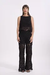 Pantalón negro de crochet con diseño floral calado y corte palazzo.