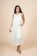 Vestido midi color crema, de corte recto y cuello redondo. Presenta bolsillos laterales y diseño sin mangas.