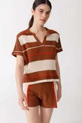 Polo tejido a rayas horizontales color marrón, beige y naranja, de corte holgado, cuello clásico y bordado de ají en el pecho.