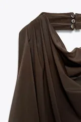 Top marrón con cuello halter, escote drapeado, detalle de pliegues y cierre trasero con cremallera oculta.