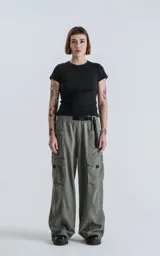 Pantalón cargo de silueta oversize, color gris oscuro/verde militar, con cintura elástica y cinturón de cinta negra ajustable con hebilla de plástico. Presenta bolsillos cargo amplios a los lados de las piernas.