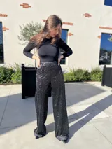 Pantalón negro con lentejuelas plateadas, de corte palazzo y cintura alta.