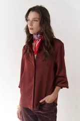 Camisa de satén de corte clásico, color azul, con botones frontales y mangas abullonadas.