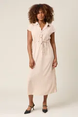 Vestido camisero color beige, con cuello, botones en el frente y lazo ajustable en la cintura.