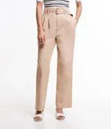 Pantalón pantacourt color beige, confeccionado en tricolina. Presenta cintura clochard con trabillas, pliegues delanteros y bolsillos laterales. Incluye cinturón con hebilla rectangular con estampado carey.
