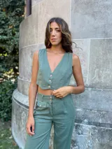 Pantalón verde de lino, de corte recto y tiro alto, con bolsillos laterales y cierre frontal con botón y cremallera.