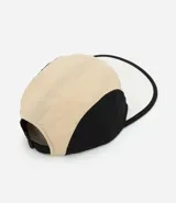 Gorra de microfibra beige y negra, modelo de 5 paneles con visera plana, etiqueta frontal y ajuste trasero con velcro.