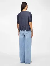 Blusa azul de mangas 3/4 con cuello redondo, botones y volantes.
