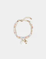 Pulsera multicadena con una cadena de mostacillas de colores y otra dorada de eslabones. Incluye dijes colgantes: un corazón de nácar y un delfín dorado.