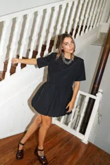 Vestido corto negro con corte en la cintura y falda balloon, de manga corta y cuello redondo.