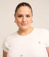 Blusa de ribana de algodón color blanco, con cuello redondo, sin mangas, fruncidos laterales y aplicación de perlas artificiales y strass.
