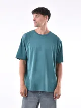 Remera gris de corte oversized, cuello redondo y mangas cortas. 