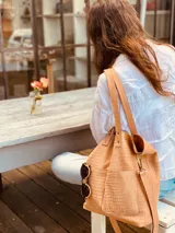 Cartera tipo tote bag color beige con textura símil cocodrilo, doble asa corta y correa larga extraíble y ajustable. Tiene dos bolsillos externos grandes y cierre superior con botón a presión.