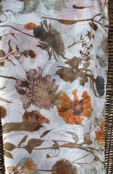 Chalina rectangular de tela traslúcida color blanco con estampado de flores y hojas en tonos marrón, naranja, verde y rosa.