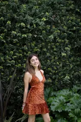 Vestido corto de lentejuelas color verde oliva, con escote en V, breteles finos cruzados en la espalda, cut-outs laterales y volado en el ruedo.