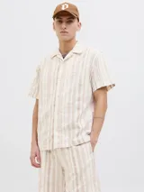 Camisa de manga corta con botones, cuello resort y corte relajado. Diseño a rayas verticales color beige y blanco.
